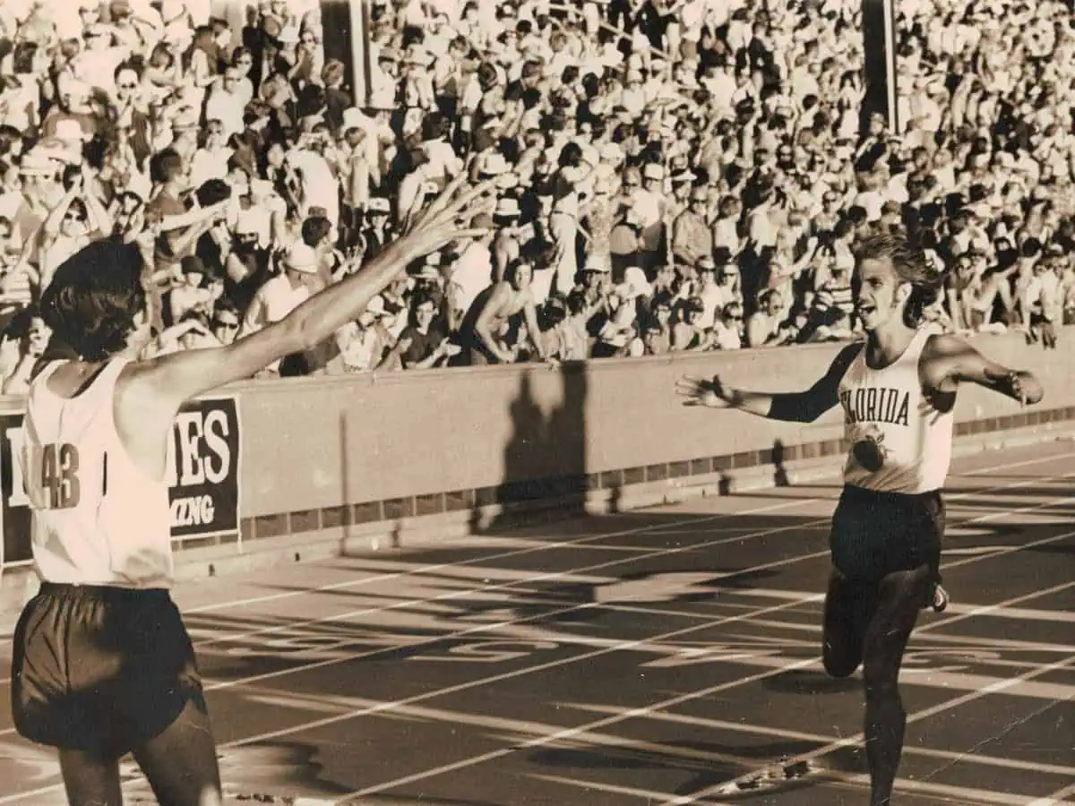 Two runners celebrate crossing finish line in stadium. 10k trials, Jeff Galloway