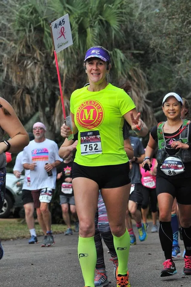 Amy Magato sets the Run Walk Run pace for fellow 'Jeffers' in a neon yellow shirt holding the pace time 4:45 flag.