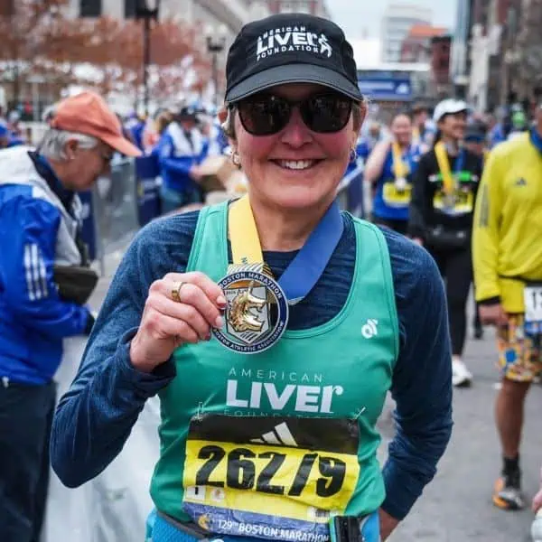 Cheri Whitt smiling with medal at Boston Marathon finish line.